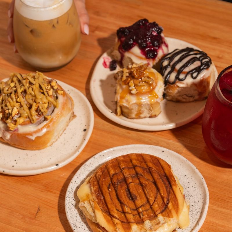 Mesa con cuatro rolls con topping, un iced latte y un tostado